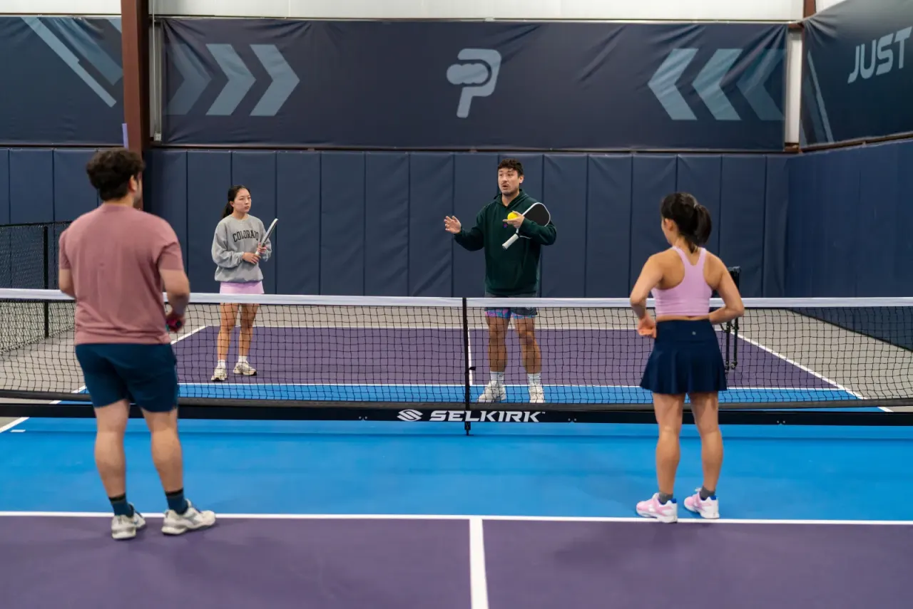 Coach assessing players' strokes during a lesson on a Pickleland court