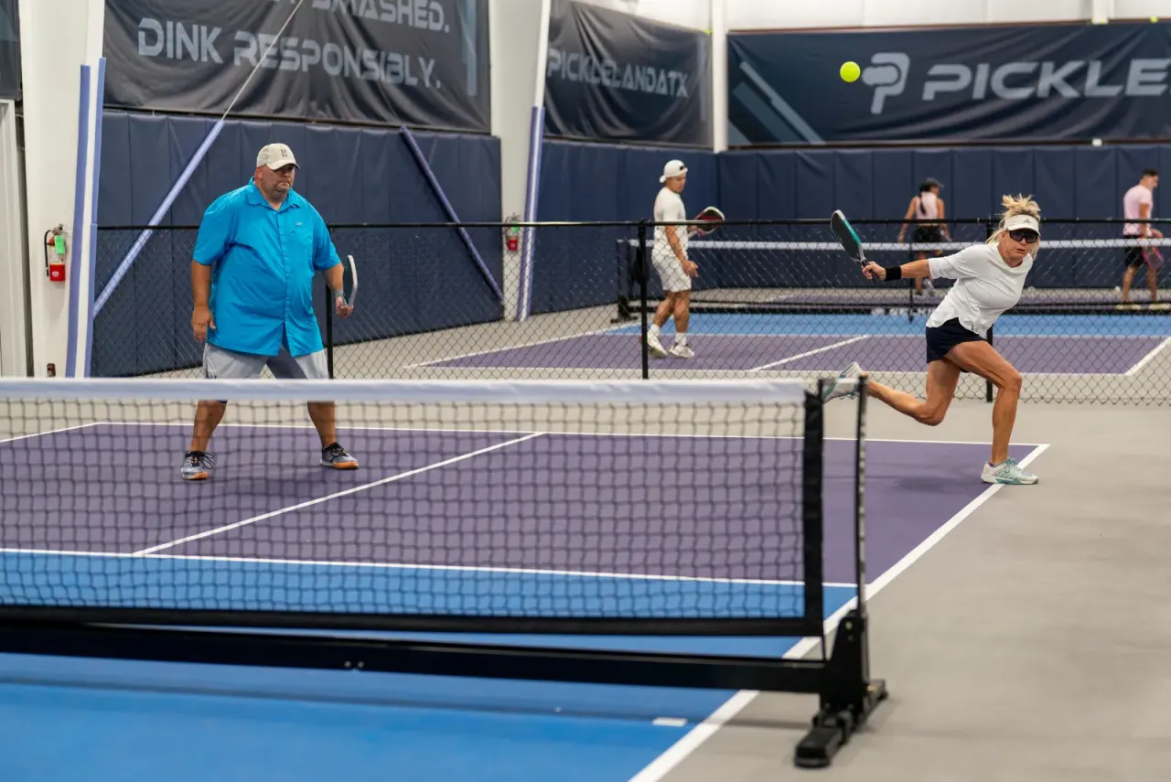 Wide view of doubles play on an indoor Pickleland court
