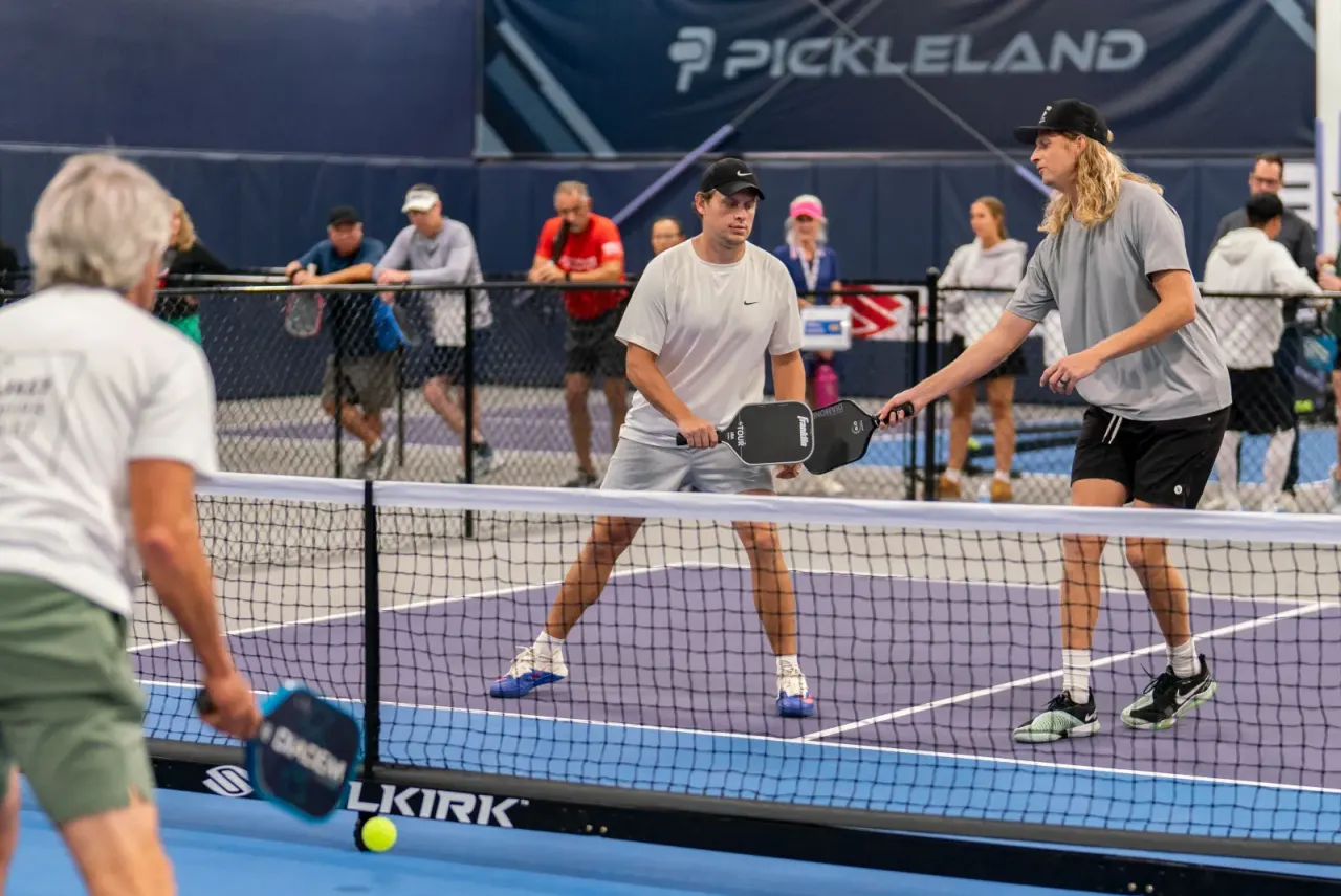 Players competing in a tournament match with spectators at Pickleland