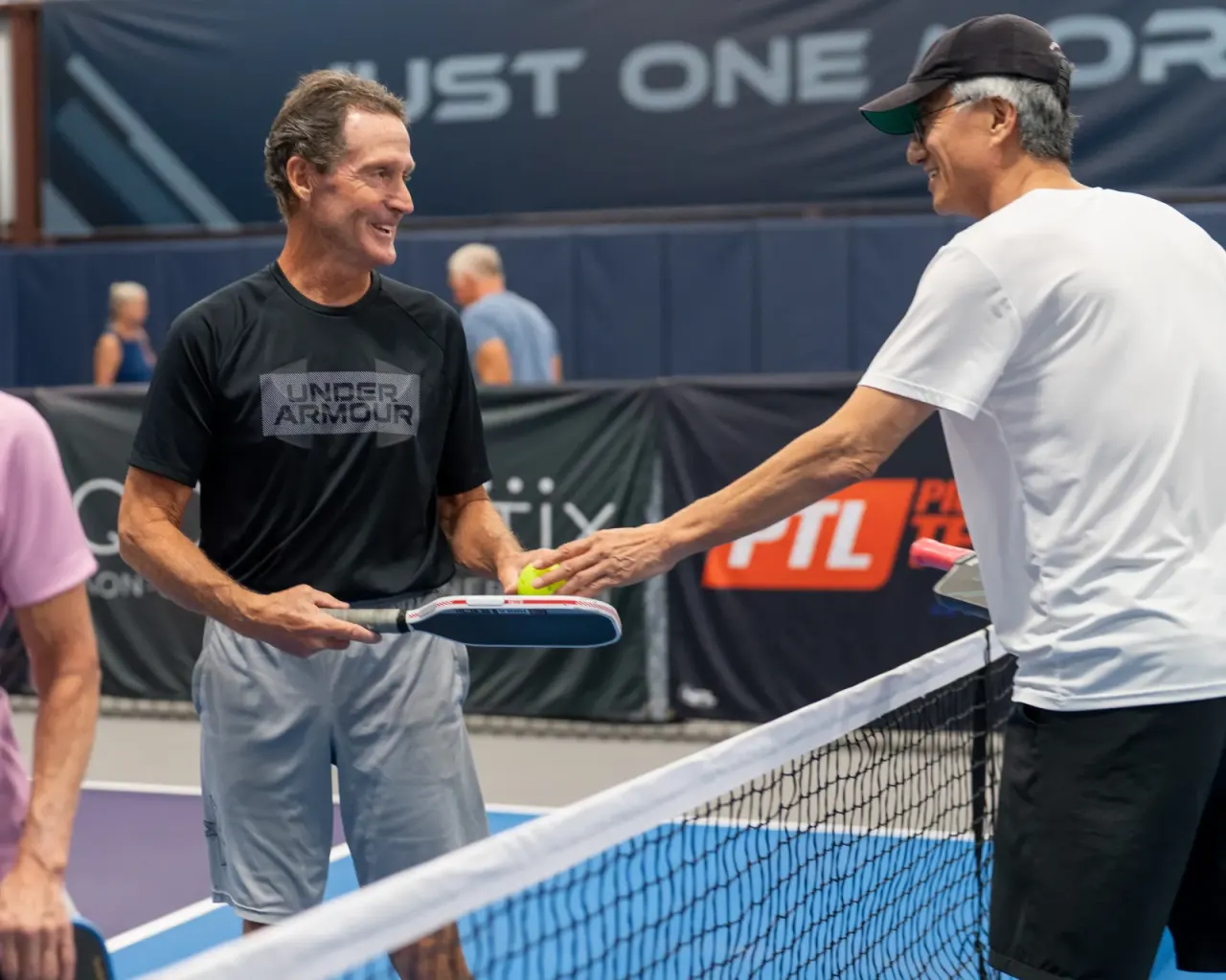 Two players shaking hands over the net in good sportsmanship