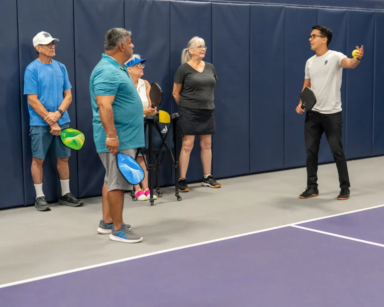 Instructor teaches a group of adult beginners during an intro pickleball lesson