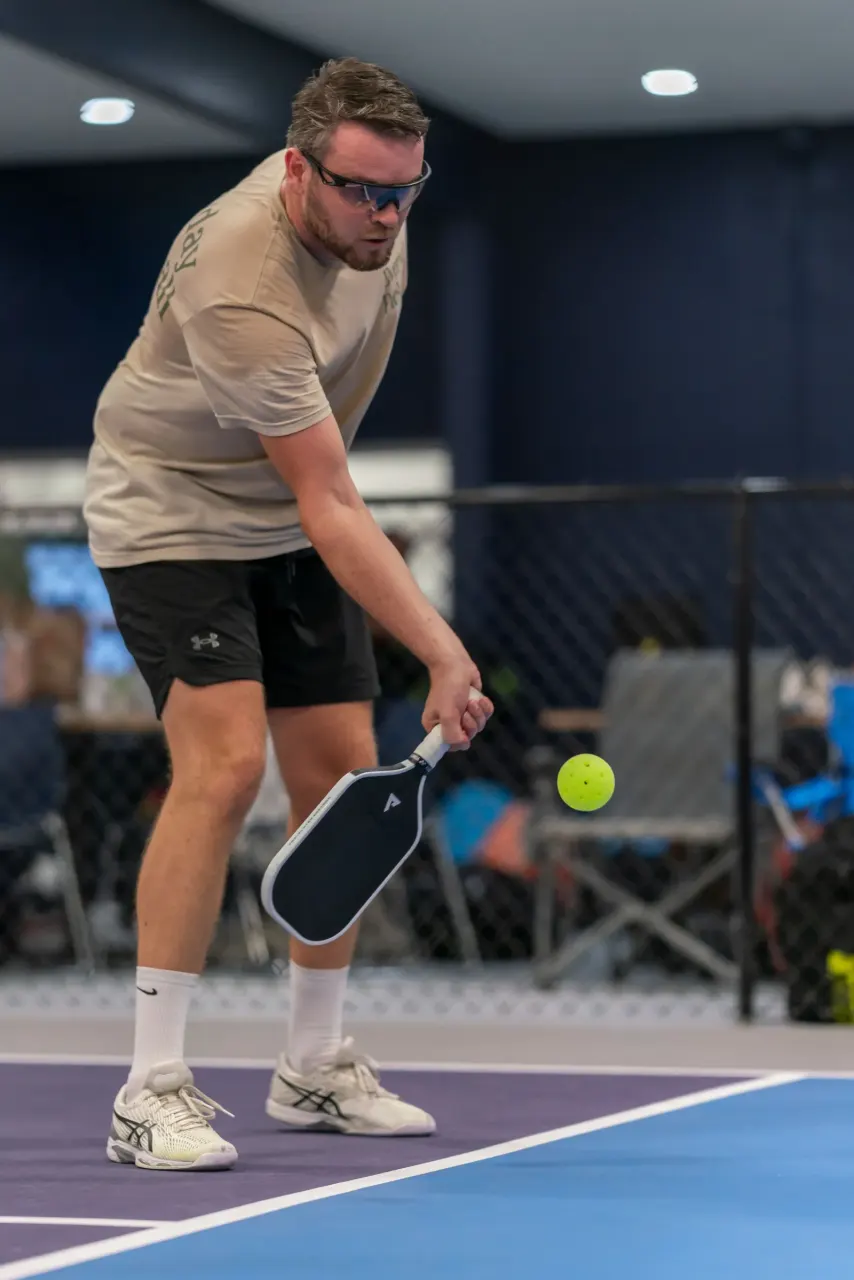 Pickleland player striking the ball with an underhand swing during a serve