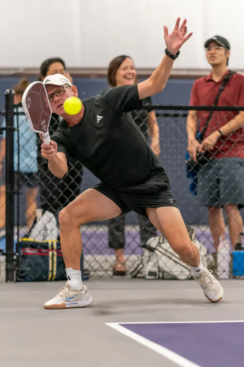 Player hitting an overhead serve during a tournament at Pickleland