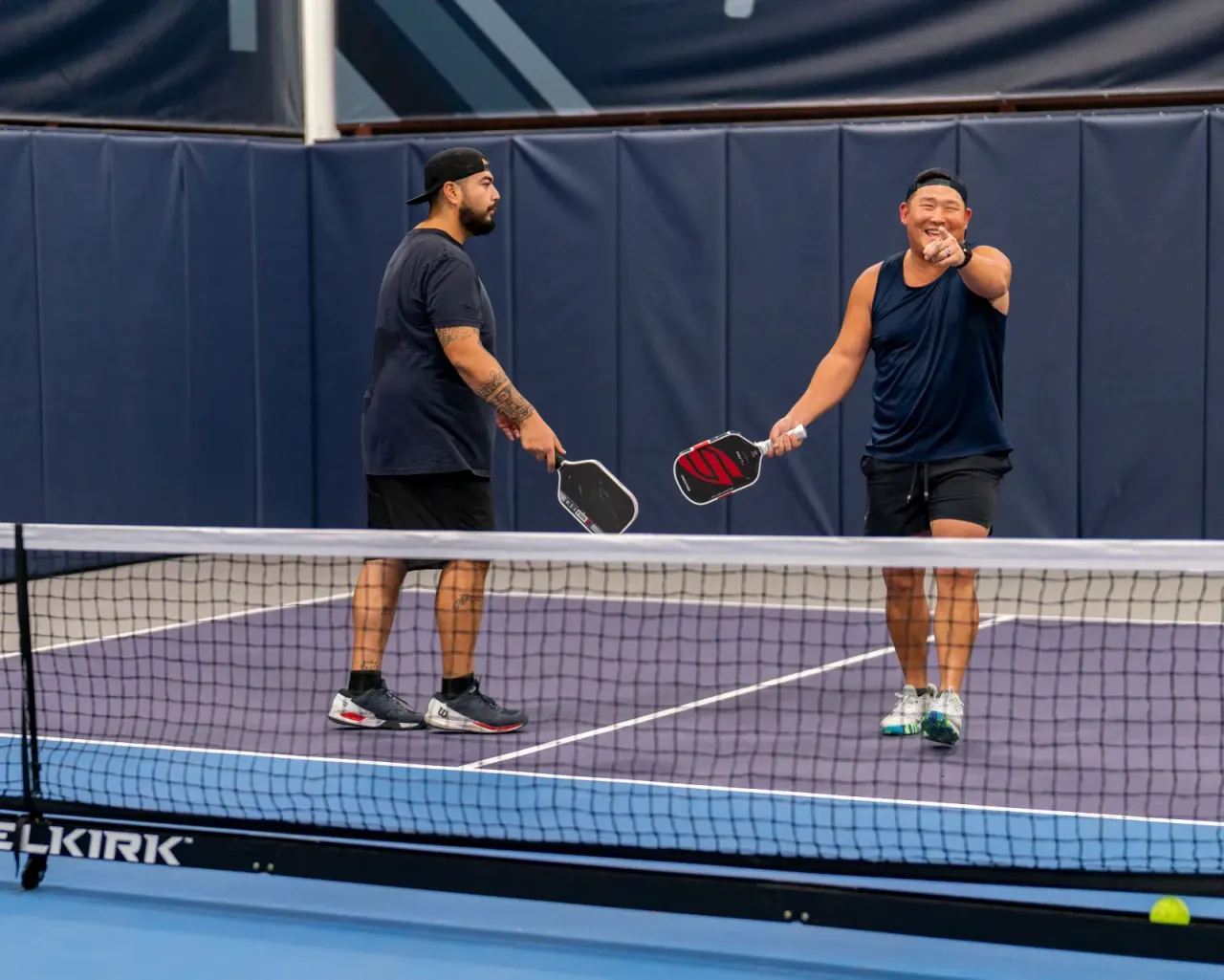 Men's doubles rally at the net during a league match