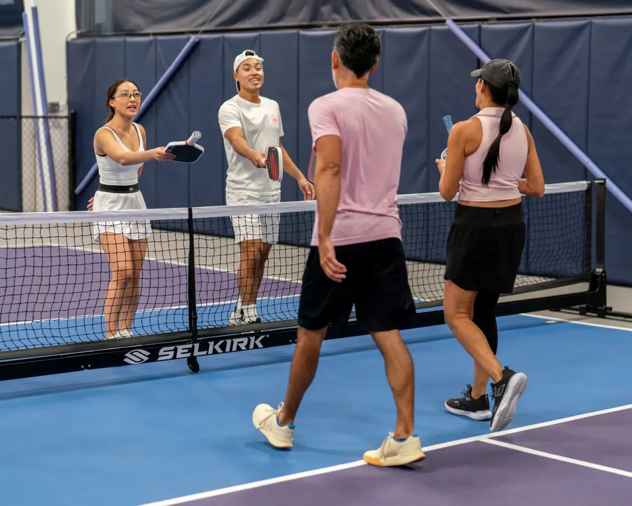 Four young players greeting each other at the net after a game