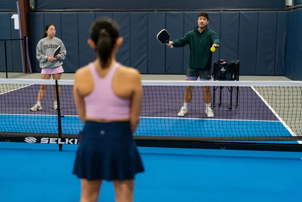 Private coaching lesson with a coach feeding balls at the net