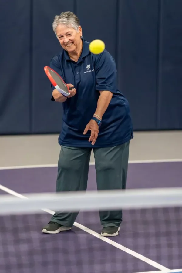 Esther, Welcome Desk & hostess at Pickleland, returns a shot on court