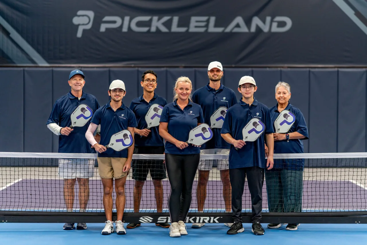 The full Pickleland team gathered on court under the Pickleland sign