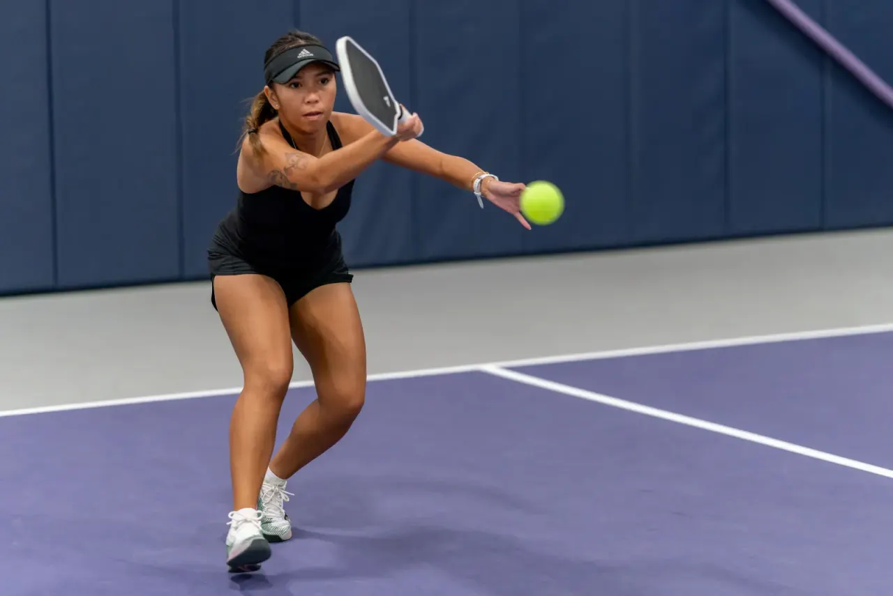 A player drives a backhand during fast-paced singles pickleball action