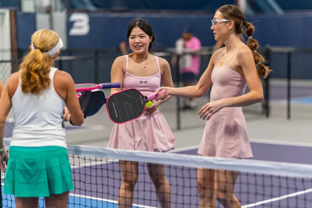 Women chatting at the net during a social pickleball session at Pickleland