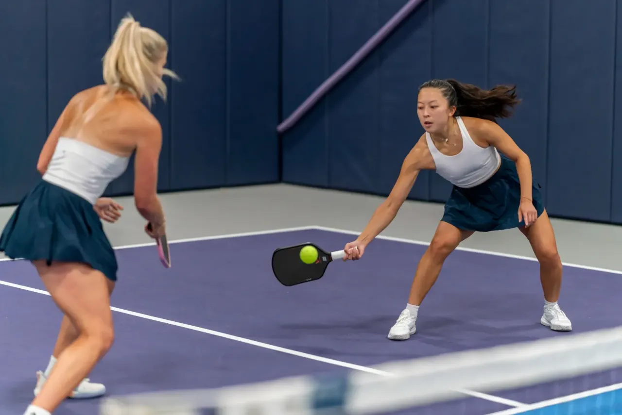Two young women playing doubles at the net