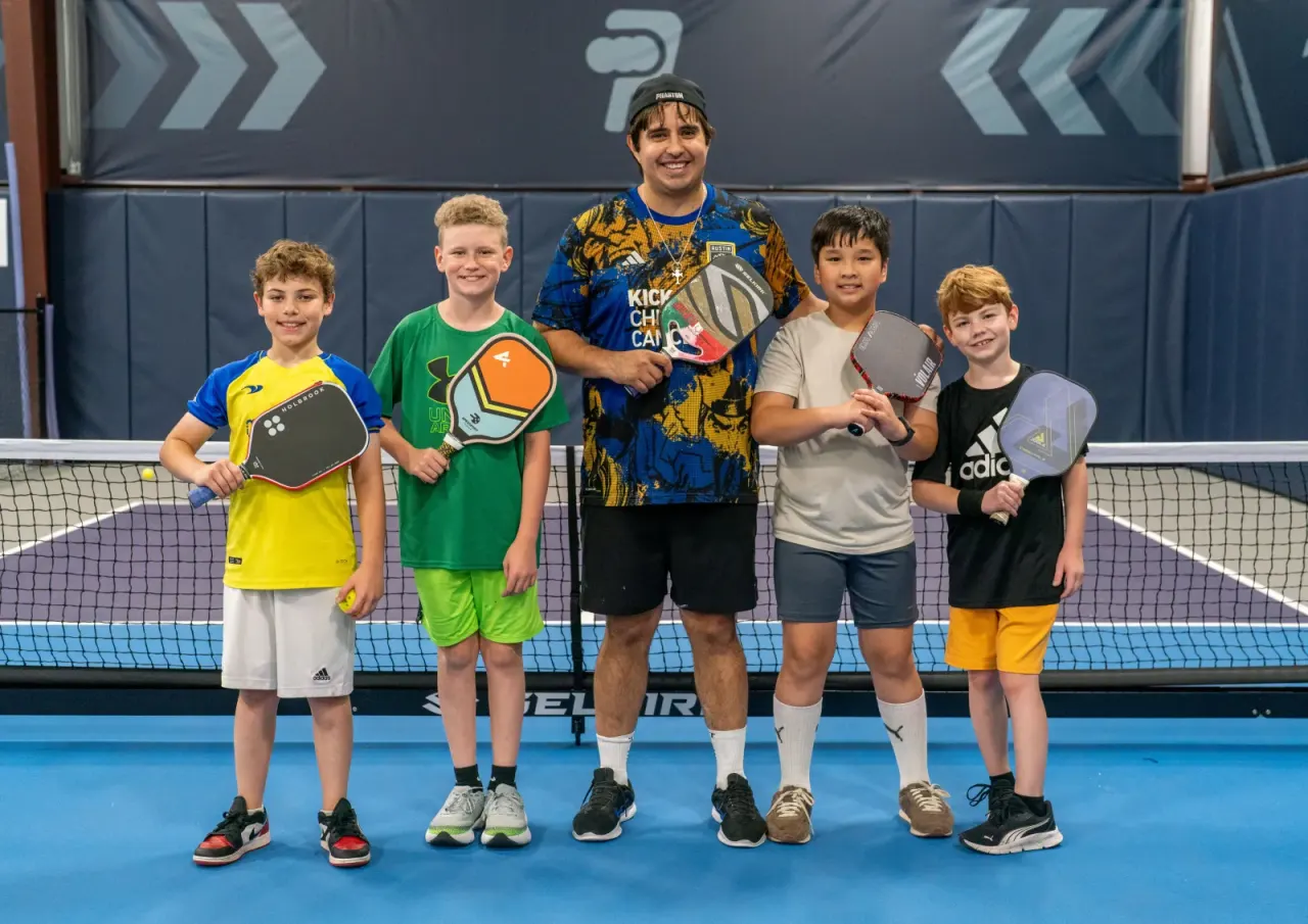 Young boys pose with a coach and paddles