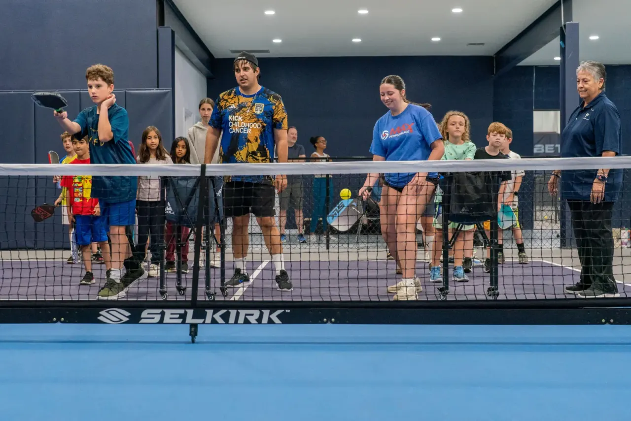 Kids gather at the net with their instructor
