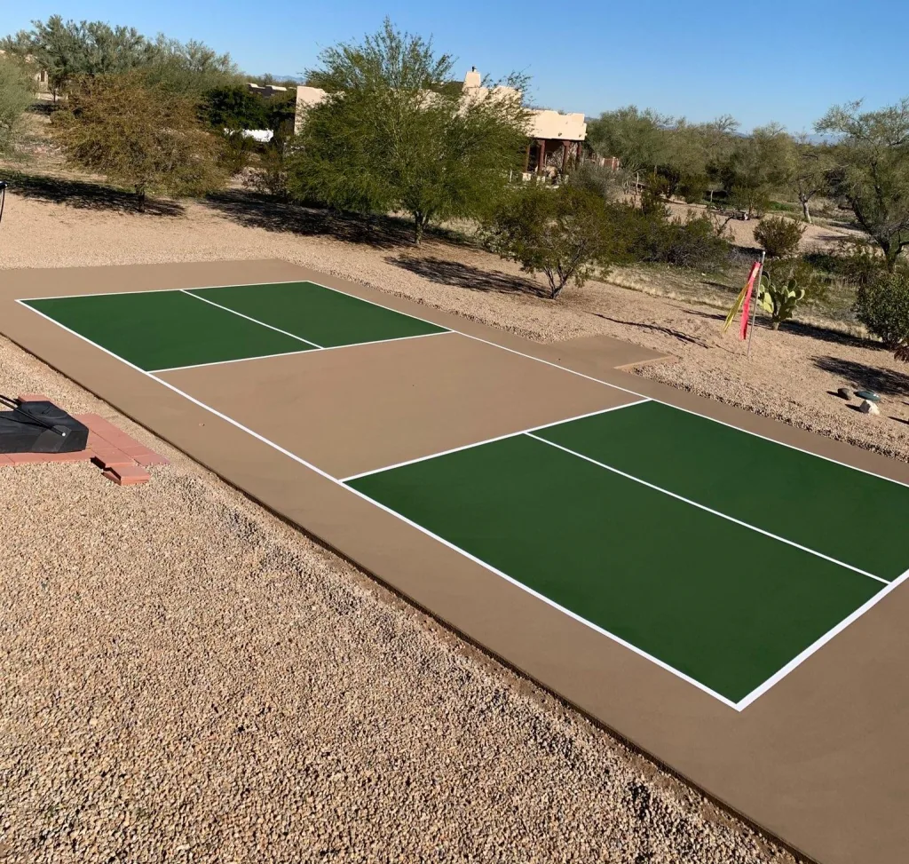 A finished backyard pickleball court with freshly painted green playing surface and crisp white regulation lines