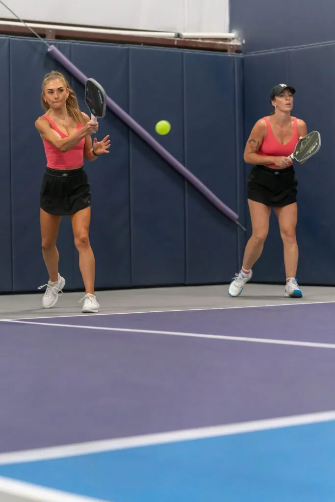 Player holding a pickleball paddle outdoors on a windy court